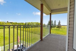 Upper-level balcony featuring concrete flooring, white metal railings, and natural wood support columns - 