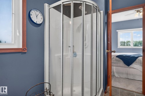 Curved glass shower enclosure with white base, set against a blue wall with wood trim around the window - 50336 Range Road 280, Rural Leduc County, AB - Indoor Photo Showing Other Room
