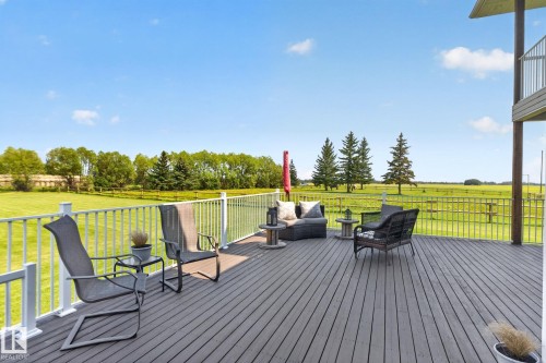 Expansive composite deck featuring horizontal wood-finish decking, white aluminum railing, and multiple seating zones overlooking manicured grounds - 50336 Range Road 280, Rural Leduc County, AB - Outdoor With Exterior