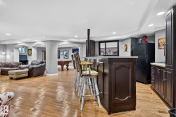 Entertainment area featuring a dark wood-finish bar with seating, recessed lighting, and wood-finish flooring - 