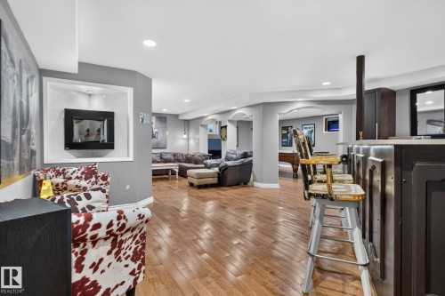 Spacious entertainment area featuring wood-finish flooring, recessed lighting, and a built-in wall niche with an inset fireplace - 50336 Range Road 280, Rural Leduc County, AB - Indoor