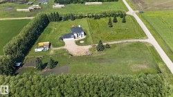 Spacious property featuring a large residence with an attached garage, surrounded by expansive green lawns - 