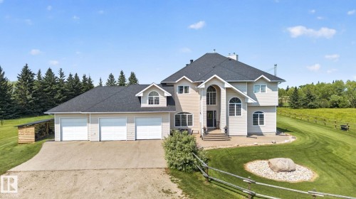 Expansive property featuring a two-story residence with a multi-car garage, dark shingle roofing, and a prominent arched entryway - 50336 Range Road 280, Rural Leduc County, AB - Outdoor With Facade