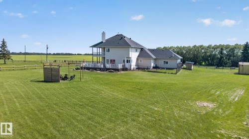 Expansive green lawn surrounds a multi-level residence featuring a dark shingle roof and a cream-colored exterior - 50336 Range Road 280, Rural Leduc County, AB - Outdoor