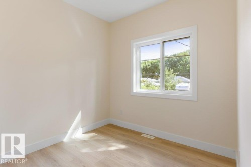 Bedroom 1 - Room featuring a double-paned window with white trim, light-toned walls, wood-finish flooring, and white baseboards - 10323 79 Street Nw, Edmonton, AB - Indoor Photo Showing Other Room