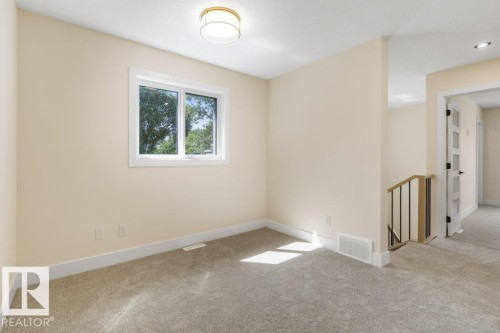 Carpeted room with a double-pane window, neutral-toned walls, white baseboards, and a contemporary ceiling light fixture - 10323 79 Street Nw, Edmonton, AB - Indoor Photo Showing Other Room