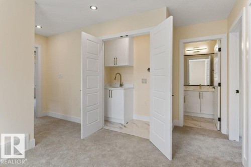 Spacious primary suite featuring a dedicated walk-in closet with double doors, dual vanity bathroom with framed mirror and brushed nickel hardware, neutral wall finishes, and recessed ceiling lighting - 10323 79 Street Nw, Edmonton, AB - Indoor Photo Showing Other Room