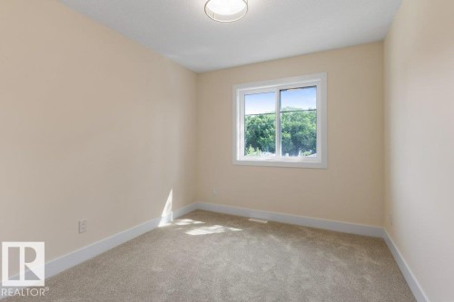 Bedroom 4 - Carpeted room featuring a white-framed window overlooking mature trees, light neutral-toned walls, white baseboards, and a semi-flush ceiling light fixture - 10323 79 Street Nw, Edmonton, AB - Indoor Photo Showing Other Room