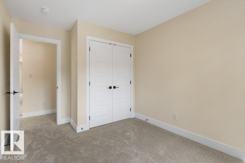 Bedroom 4 - Spacious bedroom featuring neutral wall finishes, neutral-toned carpet flooring, white panel closet doors with black hardware, and an open floor plan with direct access to an adjoining hallway - 10323 79 Street Nw, Edmonton, AB - Indoor Photo Showing Other Room