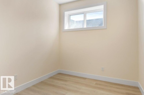 Bedroom 5 - Room featuring light-colored walls, wood-finish flooring, white baseboards, and a white-framed window - 10323 79 Street Nw, Edmonton, AB - Indoor Photo Showing Other Room