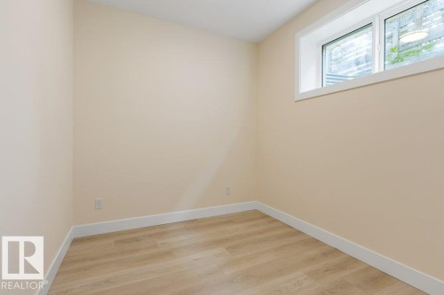 Bedroom 6 - Light-filled room featuring a single window, neutral wall tones, wood-finish flooring, and crisp white baseboards - 10323 79 Street Nw, Edmonton, AB - Indoor Photo Showing Other Room