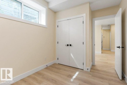 Bedroom 6 - Neutral-toned room featuring light wood-finish flooring, a contemporary window, and white trim throughout - 10323 79 Street Nw, Edmonton, AB - Indoor Photo Showing Other Room