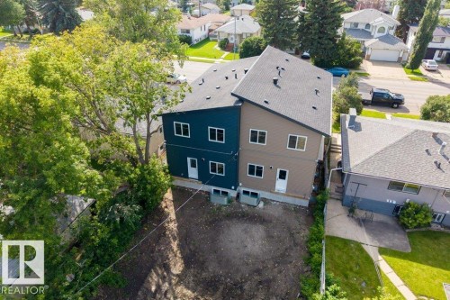 Contemporary duplex with dark teal and beige siding, multi-pitch roofs, and multiple windows on each level - 10323 79 Street Nw, Edmonton, AB - Outdoor