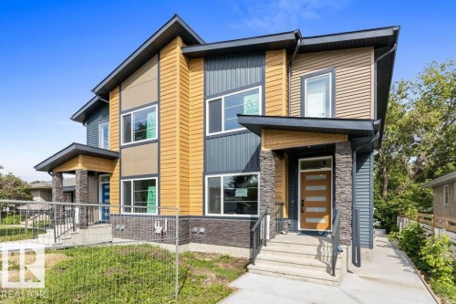 Modern two-story residence featuring a striking mixed-material exterior with warm-toned horizontal siding, stone veneer accents, and contrasting dark trim - 10323 79 Street Nw, Edmonton, AB - Outdoor With Facade