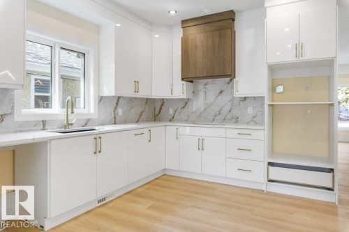 Contemporary kitchen featuring white cabinetry with brushed gold hardware, marble-look tile backsplash, and stainless steel built-in appliances including a dishwasher - 10323 79 Street Nw, Edmonton, AB - Indoor Photo Showing Kitchen