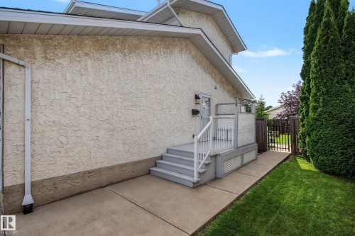 Stucco exterior with a side entry deck featuring privacy screens and an adjacent lawn area - 10032 173 Avenue Nw, Edmonton, AB - Outdoor With Exterior