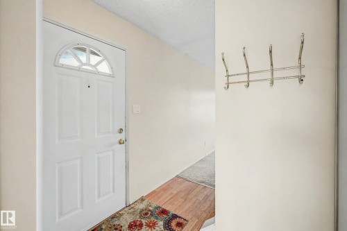 Entryway featuring a white paneled door with an arched decorative glass insert, neutral wall paint, and wood-finish flooring - 10032 173 Avenue Nw, Edmonton, AB - Indoor Photo Showing Other Room