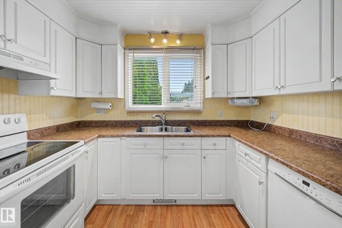 U-Shaped Kitchen featuring white cabinetry, granite countertops, and stainless steel appliances including a built-in wall oven and dishwasher - 10032 173 Avenue Nw, Edmonton, AB - Indoor Photo Showing Kitchen With Double Sink