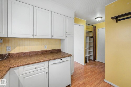 Bright and functional kitchen featuring white cabinetry, warm yellow accent walls, wood-finish flooring, and granite-style countertops - 10032 173 Avenue Nw, Edmonton, AB - Indoor