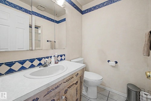 Bathroom featuring a single vanity with an integrated sink, decorative tile backsplash, wall-mounted medicine cabinet, and a toilet - 10032 173 Avenue Nw, Edmonton, AB - Indoor Photo Showing Bathroom