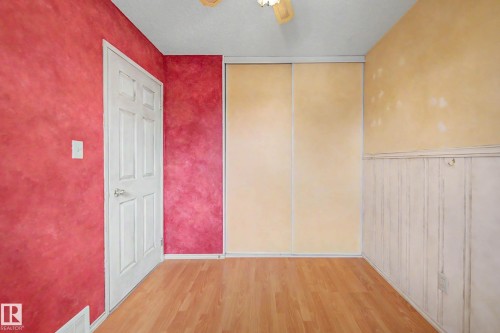 Interior room featuring wood-finish flooring, a white paneled door, and a built-in closet with sliding doors - 10032 173 Avenue Nw, Edmonton, AB - Indoor Photo Showing Other Room