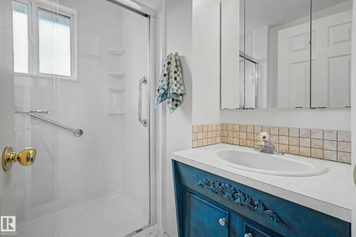 Bathroom featuring a walk-in shower with a glass enclosure, an integrated window, grab bars, and built-in shelving - 10032 173 Avenue Nw, Edmonton, AB - Indoor Photo Showing Bathroom