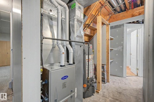 Utility room featuring a Carrier furnace, hot water heater, exposed wood joists, unfinished walls, and concrete flooring - 10032 173 Avenue Nw, Edmonton, AB - Indoor Photo Showing Basement
