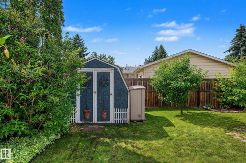 Spacious backyard featuring a blue gambrel-style shed, natural wood fencing, and established perimeter landscaping - 10032 173 Avenue Nw, Edmonton, AB - Outdoor