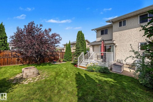 Expansive backyard featuring a manicured lawn, established trees, and a stone fire pit - 10032 173 Avenue Nw, Edmonton, AB - Outdoor