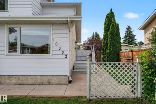 White horizontal siding exterior with a concrete sidewalk and a lattice fence - 10032 173 Avenue Nw, Edmonton, AB - Outdoor With Exterior
