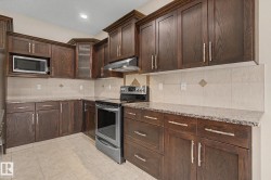 Kitchen featuring dark wood cabinetry, granite-finish countertops, and a tiled backsplash - 