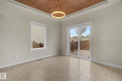 Recessed ceiling with a distinct dark wood-finish accent panel and a contemporary circular chandelier - 6016 10 Avenue Sw, Edmonton, AB - Indoor Photo Showing Other Room