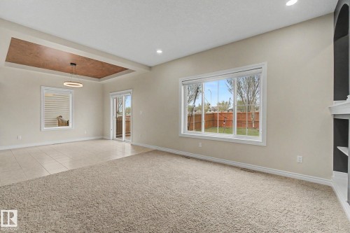 Spacious interior featuring a recessed ceiling with a contemporary pendant light fixture, large picture windows, sliding glass door access to an outdoor area, and a blend of carpet and tile flooring - 6016 10 Avenue Sw, Edmonton, AB - Indoor Photo Showing Other Room