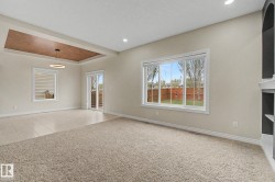 Spacious interior featuring a recessed ceiling with a contemporary pendant light fixture, large picture windows, sliding glass door access to an outdoor area, and a blend of carpet and tile flooring - 