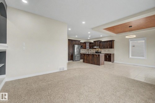 Open-concept living space featuring a spacious kitchen with dark wood cabinetry, a central island, and stainless steel appliances - 6016 10 Avenue Sw, Edmonton, AB - Indoor Photo Showing Kitchen