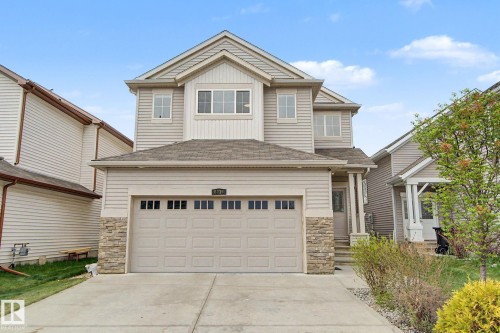 Two-story suburban residence with light siding, stone veneer accents, an attached two-car garage, and a concrete driveway - 6016 10 Avenue Sw, Edmonton, AB - Outdoor With Facade