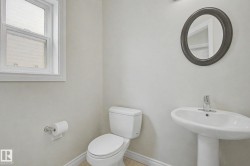 Compact bath featuring a white pedestal sink with chrome faucet, a white toilet, and a window with privacy glass - 