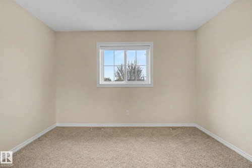 Carpeted room featuring a double-hung window with a white frame, light beige wall paint, white baseboards, and a textured ceiling - 6016 10 Avenue Sw, Edmonton, AB - Indoor Photo Showing Other Room