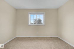 Carpeted room featuring a double-hung window with a white frame, light beige wall paint, white baseboards, and a textured ceiling - 