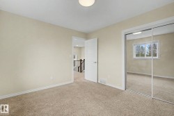 Neutral-toned carpeted room featuring a ceiling light fixture, white trim, and a mirrored sliding closet door - 