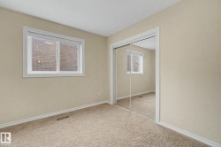 Bedroom featuring neutral carpeting, a dual-pane window with white trim, and a full-height mirrored closet - 