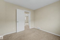 Light-toned carpeting and walls create a neutral palette, complemented by white trim and a contemporary five-panel interior door - 