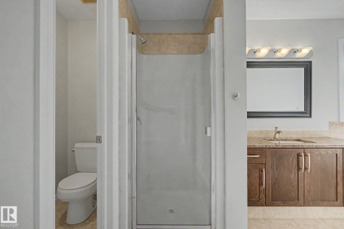 Shower enclosure with clear glass door, chrome shower head, and stone-finish wall tile - 6016 10 Avenue Sw, Edmonton, AB - Indoor Photo Showing Bathroom