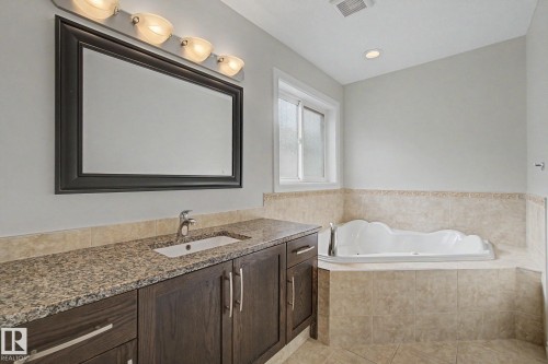 Bathroom featuring a dark wood vanity with a granite countertop, undermount sink, and a framed mirror - 6016 10 Avenue Sw, Edmonton, AB - Indoor Photo Showing Bathroom
