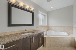 Bathroom featuring a dark wood vanity with a granite countertop, undermount sink, and a framed mirror - 