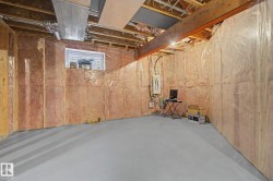 Unfinished basement featuring exposed wood joists, insulated walls, and a concrete floor - 