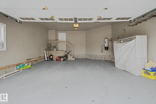 Spacious garage featuring a concrete floor, built-in stairs, and a wall-mounted central vacuum system - 6016 10 Avenue Sw, Edmonton, AB - Indoor Photo Showing Garage