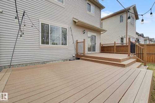 Multi-tiered wood-finish deck with integrated steps, black metal balusters, and a sliding glass door entry to the home - 6016 10 Avenue Sw, Edmonton, AB - Outdoor With Deck Patio Veranda With Exterior