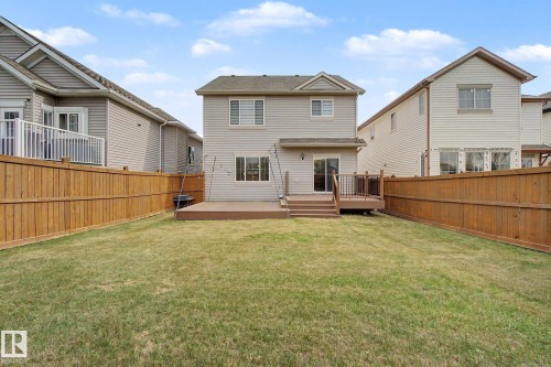 Expansive backyard featuring a large lawn, full privacy fencing, and an elevated composite deck with railing - 6016 10 Avenue Sw, Edmonton, AB - Outdoor With Deck Patio Veranda