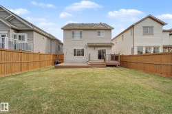 Expansive backyard featuring a large lawn, full privacy fencing, and an elevated composite deck with railing - 